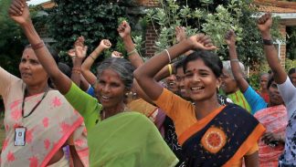 Indian women lift their arms in a cheer