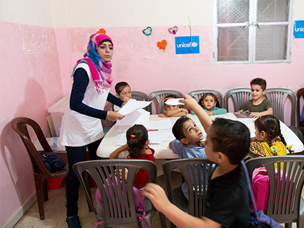 A teacher manages her class in a school at the camp