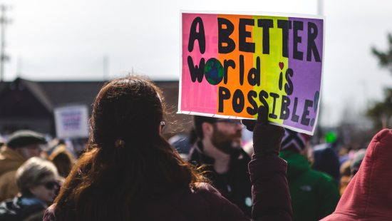 image at protest with person holding sign that says "a better world is possible"
