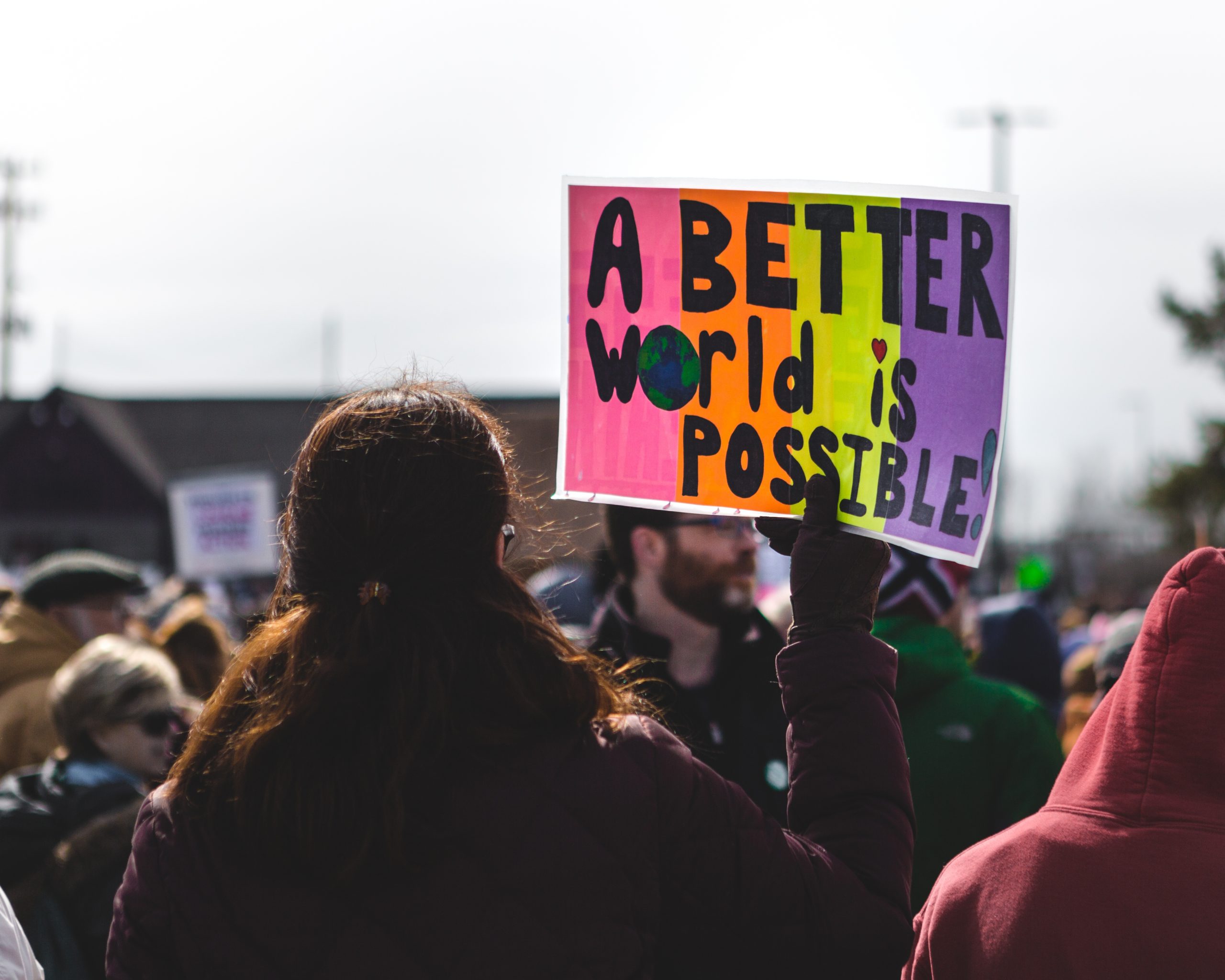 image at protest with person holding sign that says "a better world is possible"