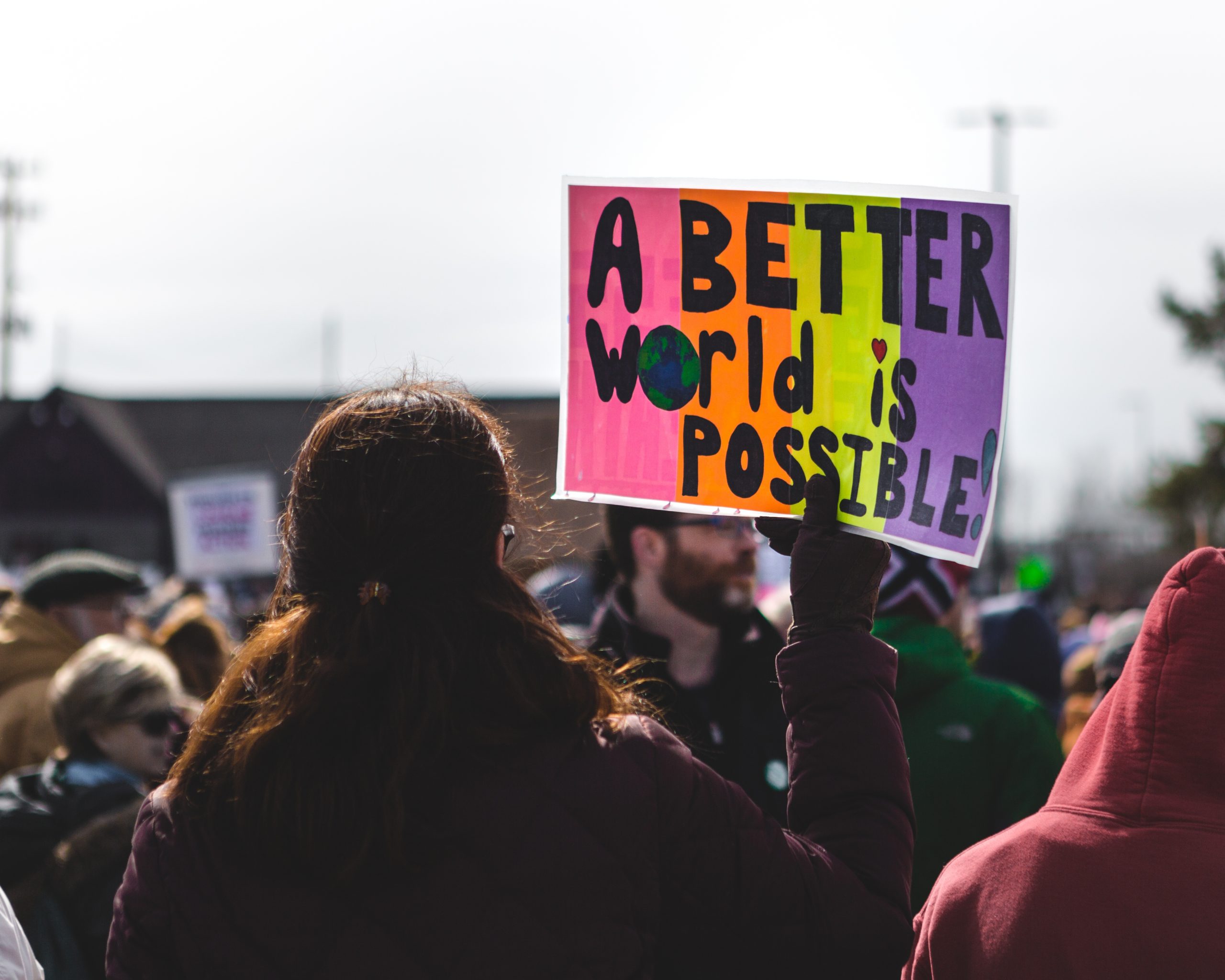 a-better-world-is-possible image at protest with person holding sign that says "a better world is possible"
