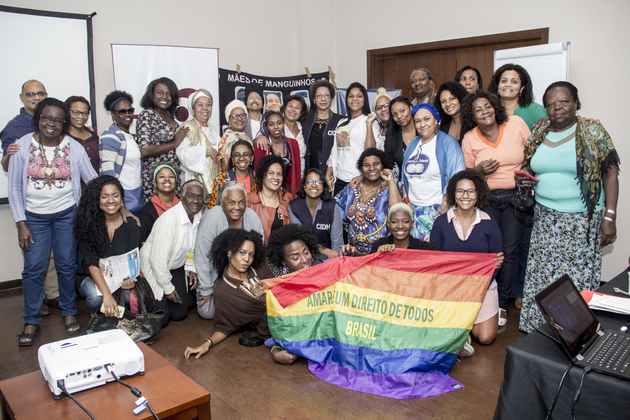 Members of Criola meet with the rapporteur from the Inter-American Commission on Human Rights of the Organization of American States to discuss human rights violations of Black women in Brazil. A group of about 30 pose together in 3 rows.