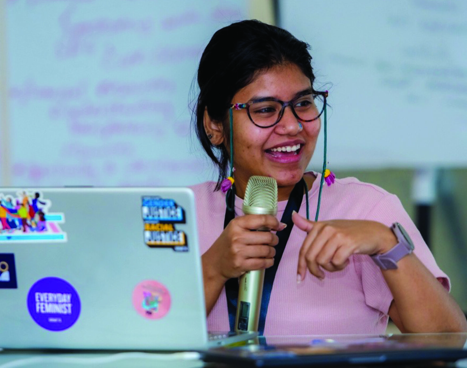 Deephshikha Ghosh speaks into a microphone while gesturing with her left hand.